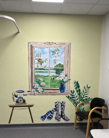 An indoor window mural with countryside view, wellies and a telephone